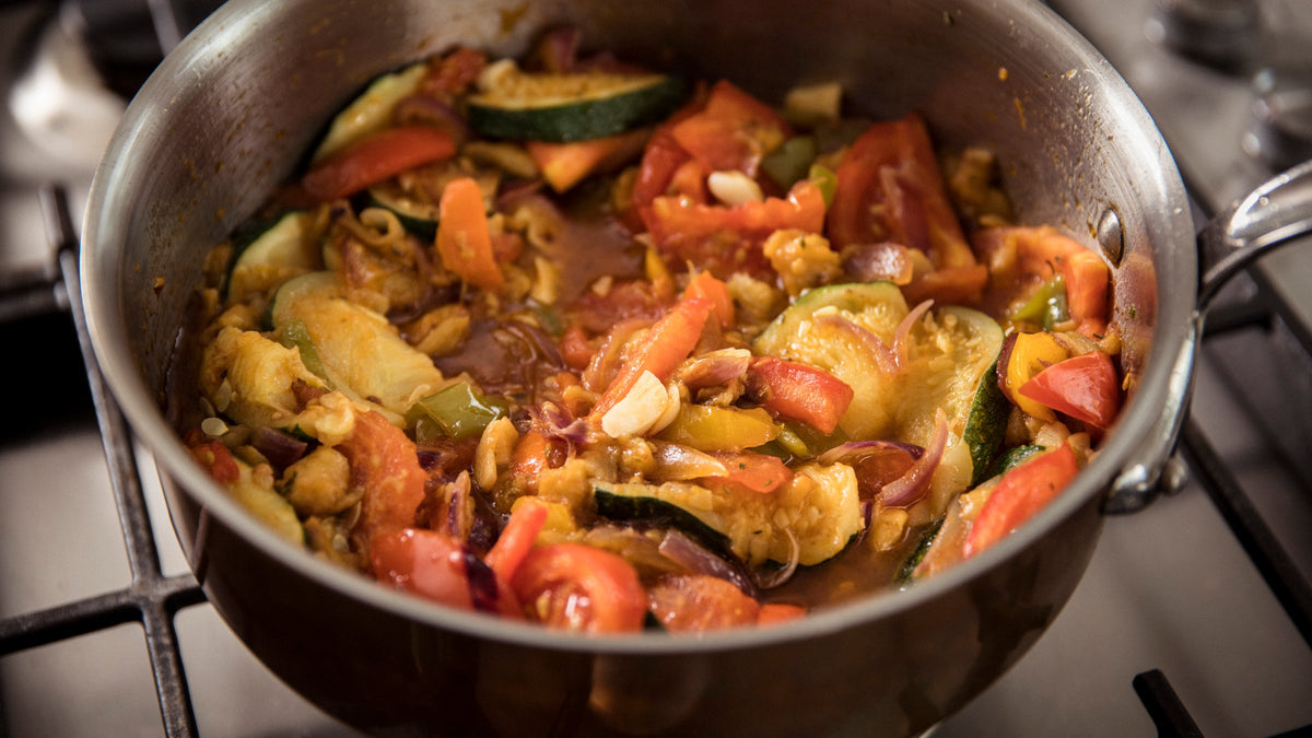 Légumes de saison qui mijotent dans une sauteuse en cuivre